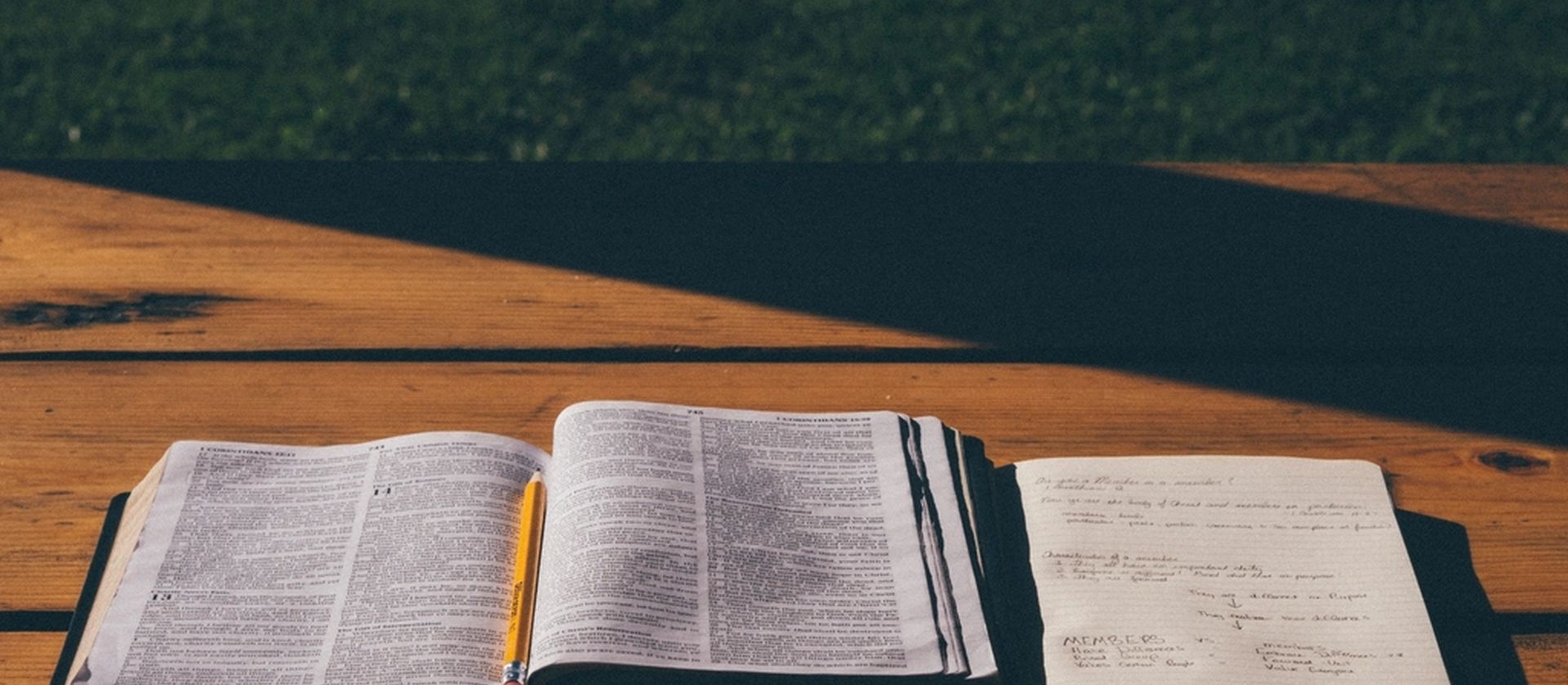 An open Bible resting on a wooden table in warm daylight